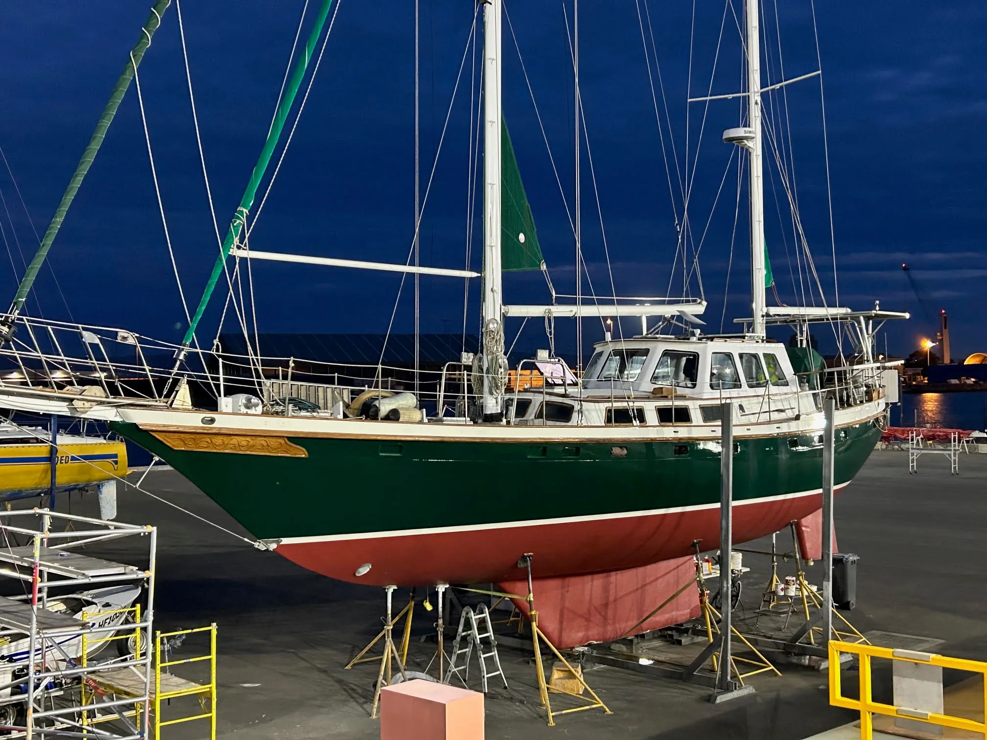 Sea Dragon on the hardstand at dusk in her new racing-green paint, scaffolding around the hull
