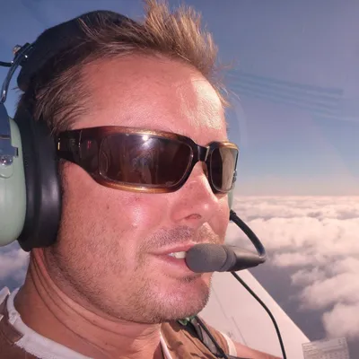 Tim in the cockpit of a light plane above the clouds
